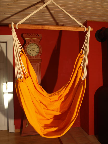 Der Hängemattensessel aus Baumwolltuch in sanftem Orange passt in jede Umgebung.